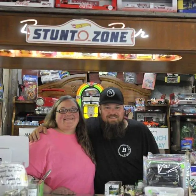 The owners of 605 Diecast behind the counter, under the Hot Wheels Stunt Zone sign
